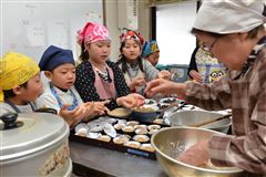 地区の方の指導を受け熱心に伝承料理を作る子どもたち